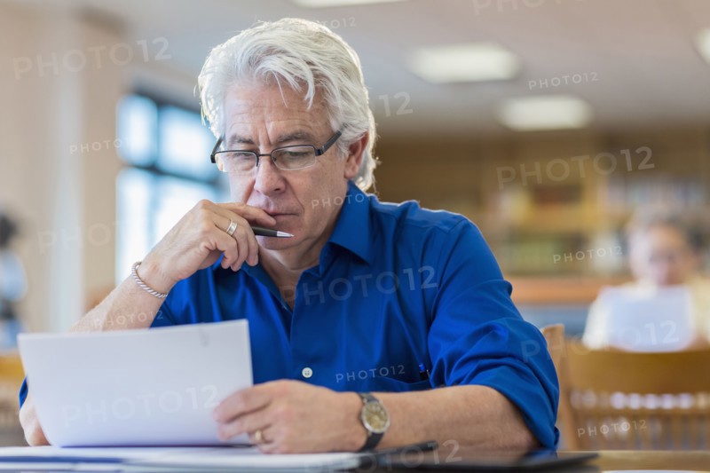 Man reading paperwork in library
