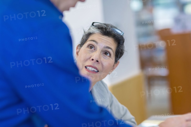 Hispanic teacher helping adult student in library