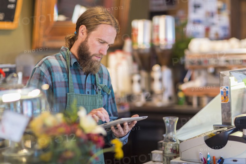 Caucasian server using digital tablet in cafe