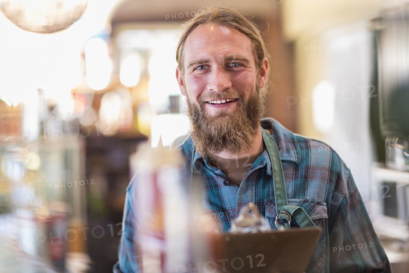 Caucasian server holding clipboard in cafe