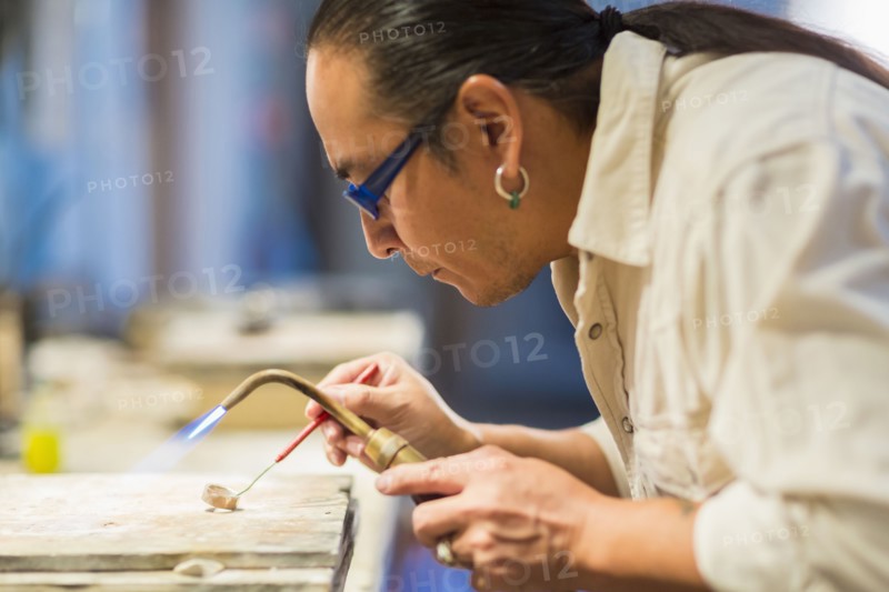 Close up of Native American jeweler using blowtorch in studio