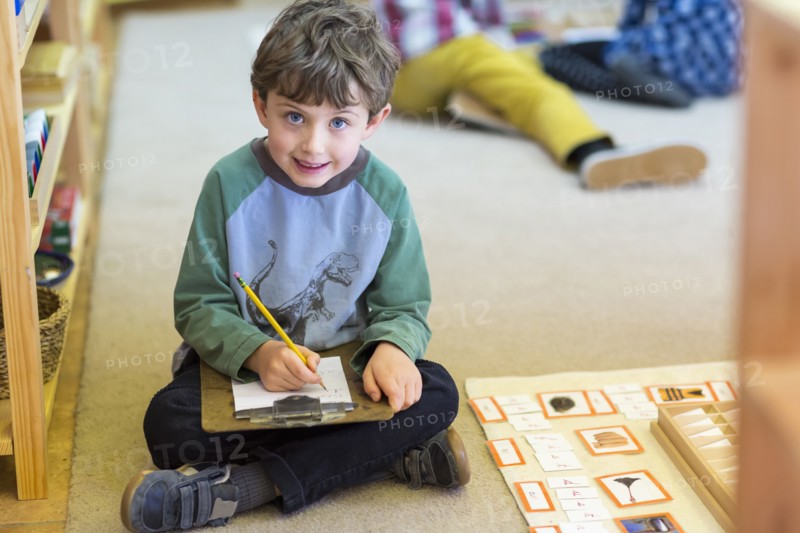 Smiling boy writing in classroom