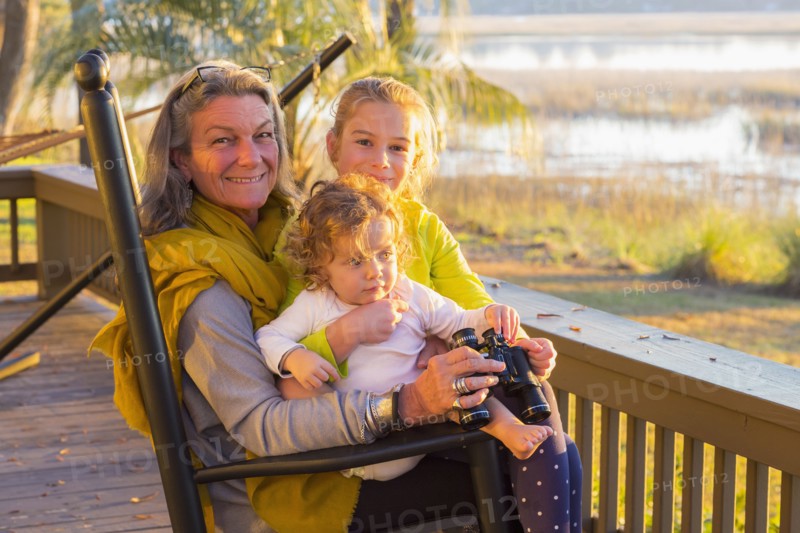 Caucasian grandmother and grandchildren using binoculars on porch