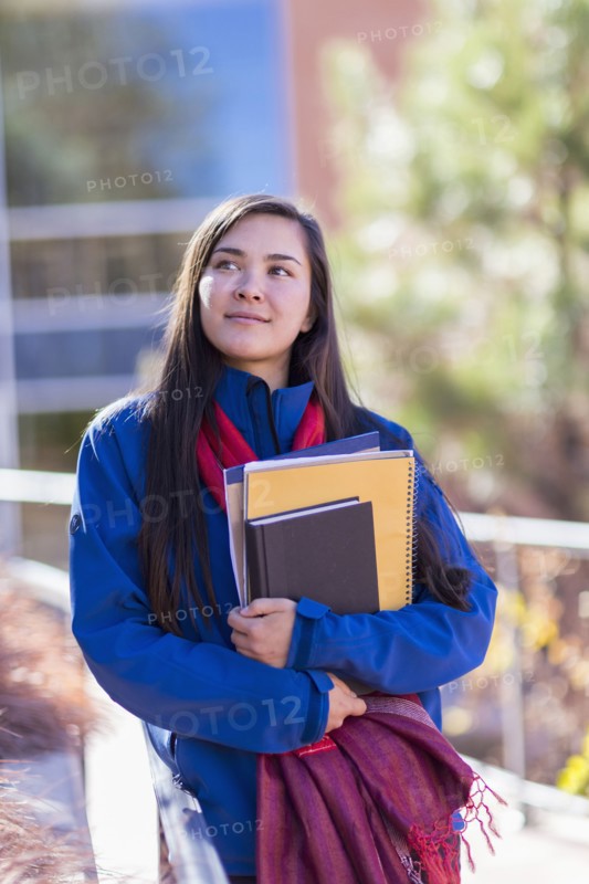 Mixed race student holding books on campus
