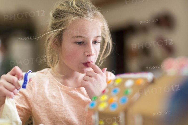 Caucasian girl decorating gingerbread house
