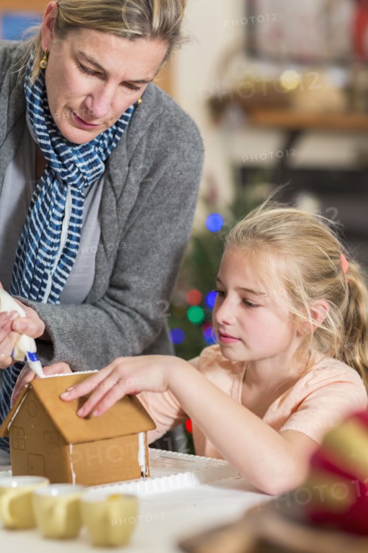 Caucasian mother and daughter decorating gingerbread house
