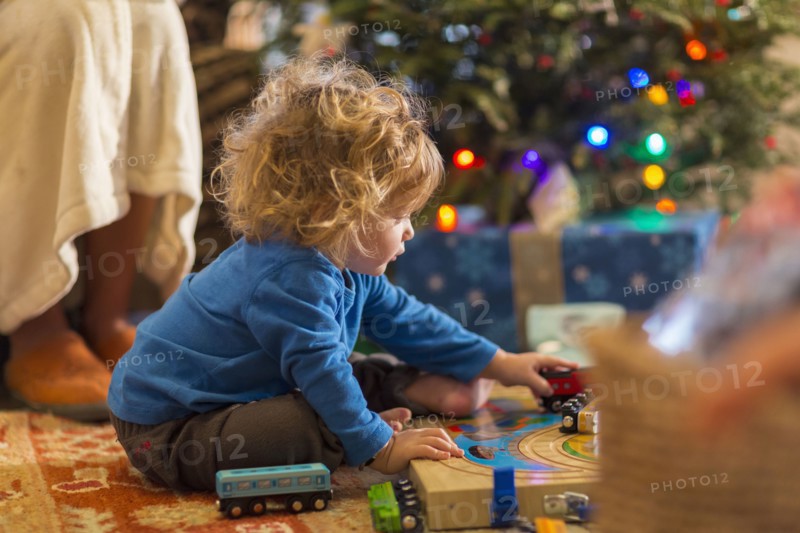 Caucasian baby boy playing with toys under Christmas tree