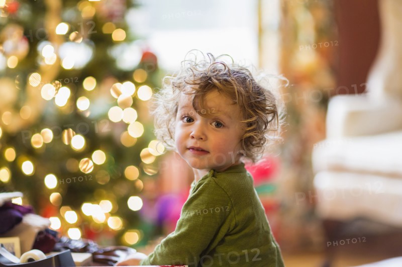 Caucasian baby boy sitting near Christmas tree