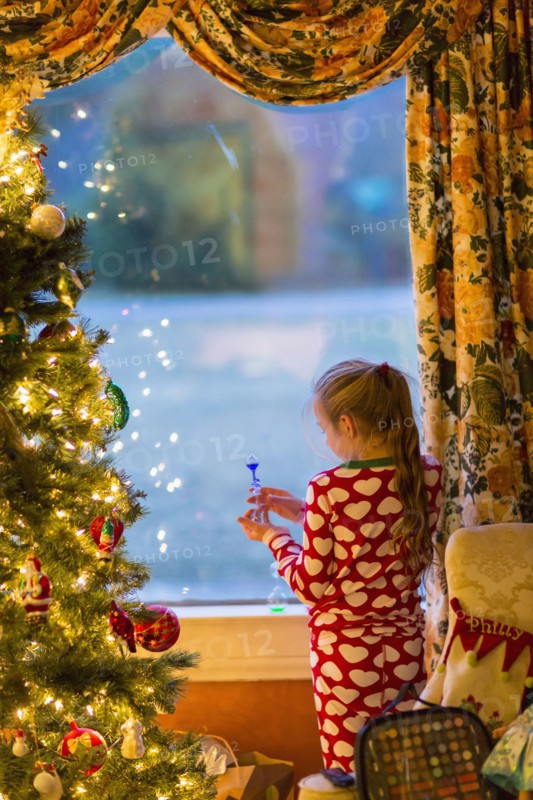 Caucasian girl opening present near Christmas tree