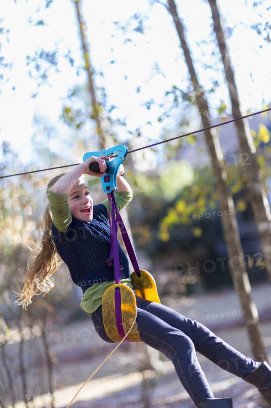 Caucasian girl zip lining in forest