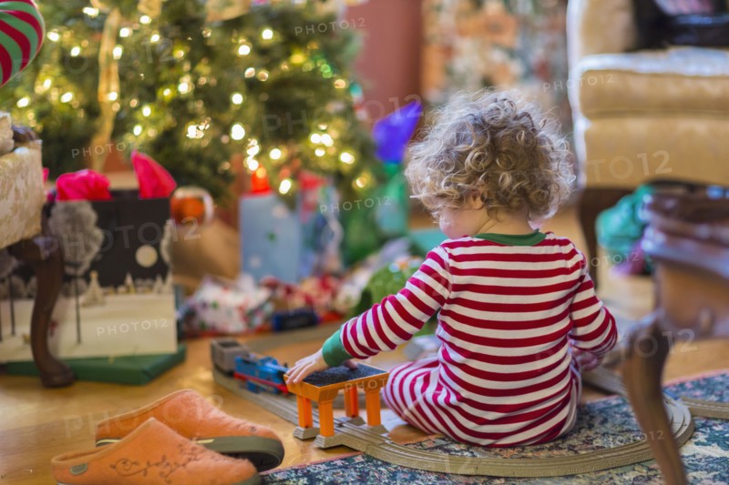 Caucasian baby boy playing with toys near Christmas tree