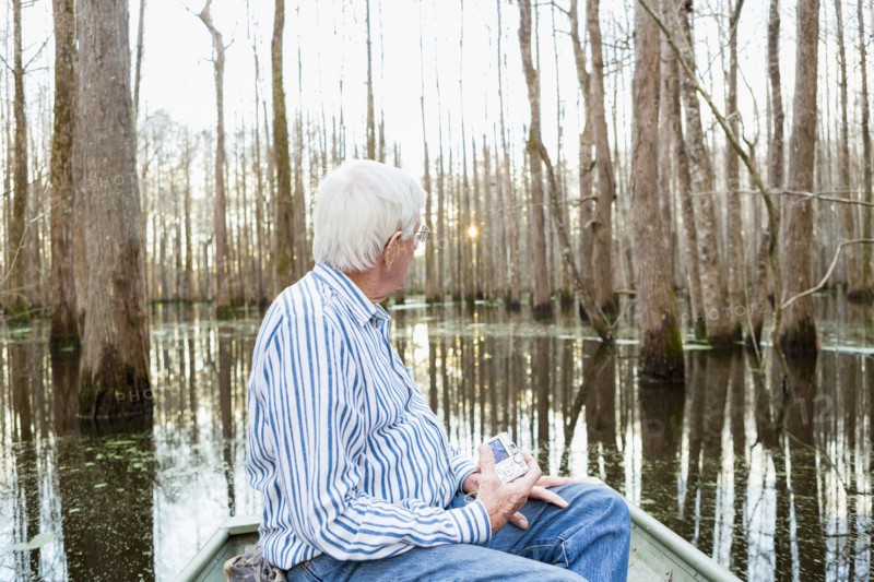 Older Caucasian man riding boat in swamp