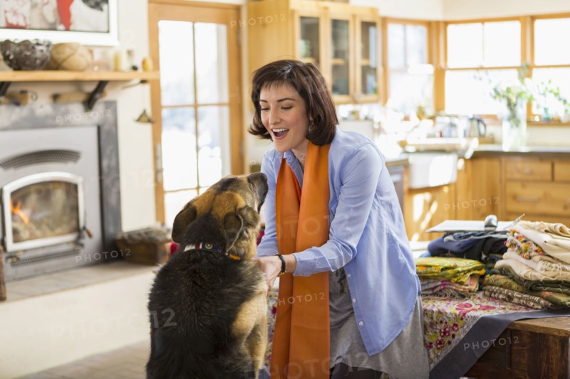 Hispanic woman petting dog in kitchen