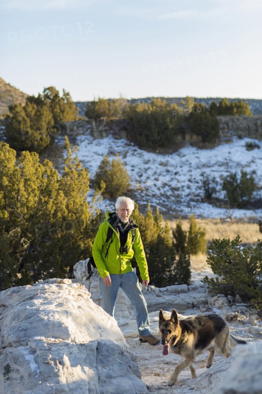 Older man and dog standing on remote rock formations