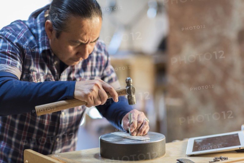 Native American artist hammering metal in studio