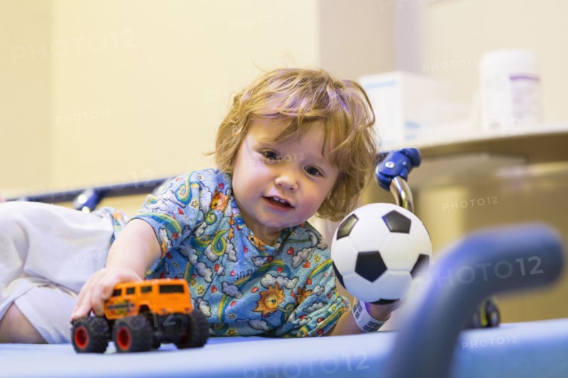 Caucasian boy playing on hospital bed
