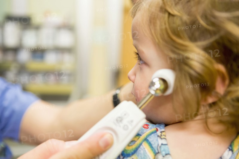 Close up of doctor taking temperature of boy with thermometer