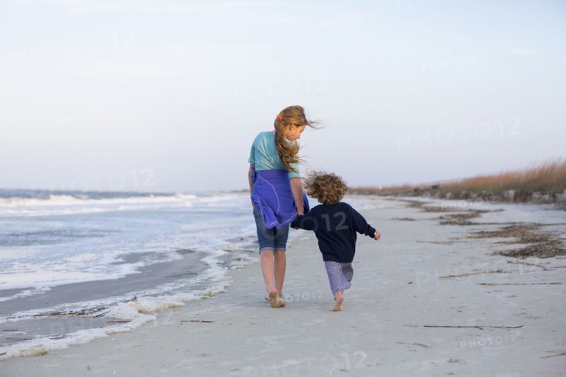Caucasian brother and sister walking on beach