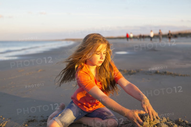 Caucasian girl building sandcastle on beach