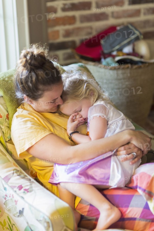 Caucasian mother holding daughter in armchair