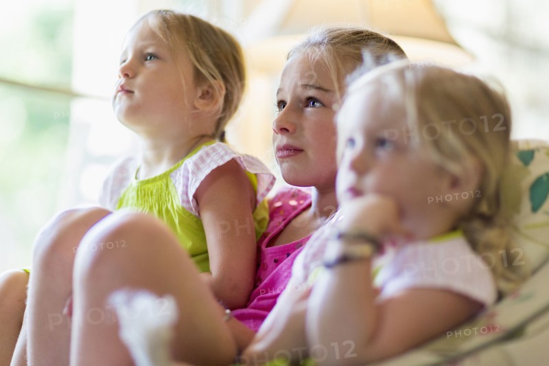 Caucasian girls watching television in armchair