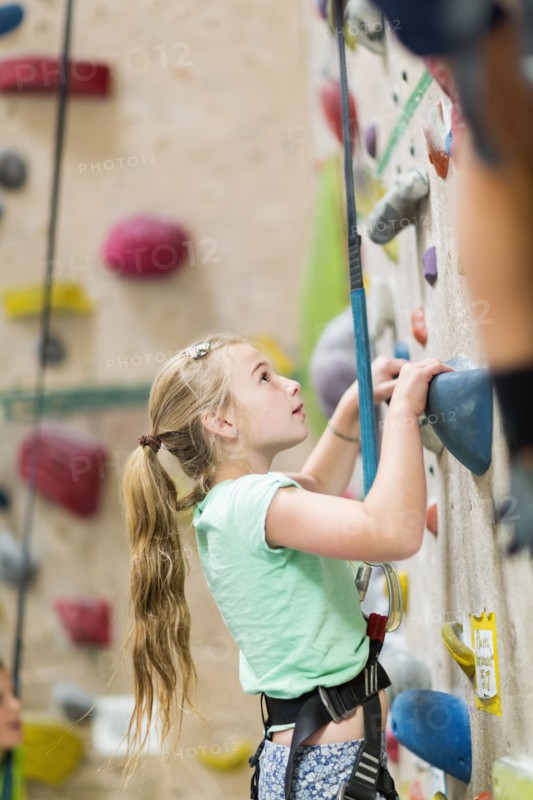Caucasian girl climbing rock wall indoors