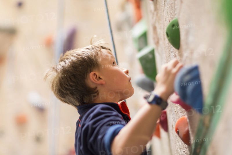 Caucasian boy climbing rock wall indoors