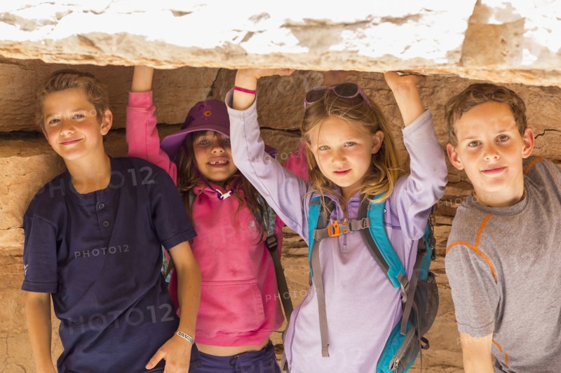 Children crouching under rock formation