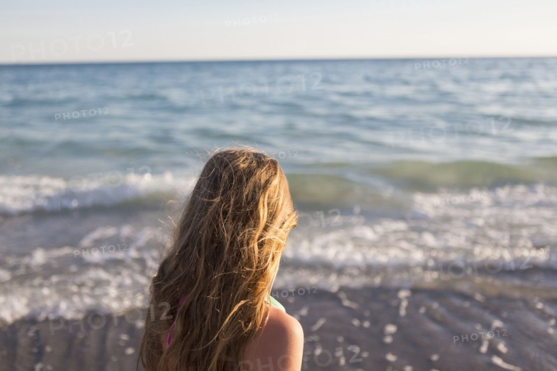 Caucasian girl watching waves on beach