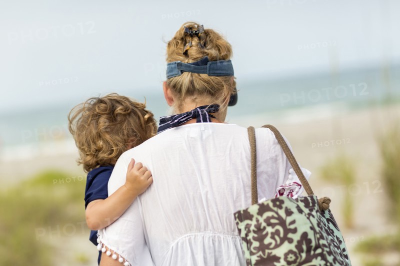 Caucasian mother carrying baby son on beach