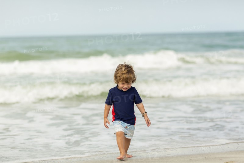 Caucasian baby boy walking on beach