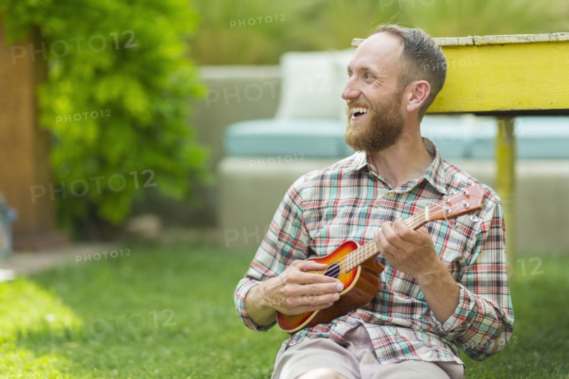 Caucasian man playing ukulele in backyard