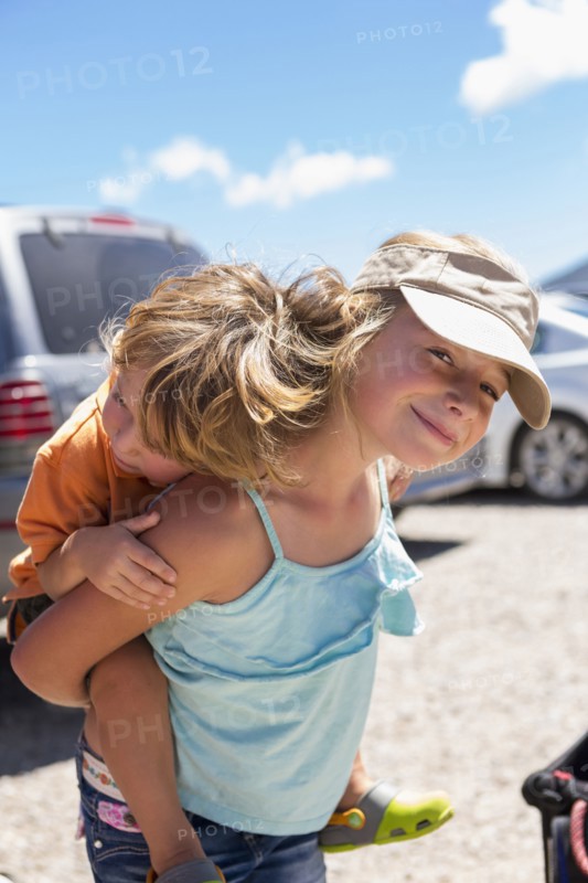 Caucasian girl carrying brother piggyback