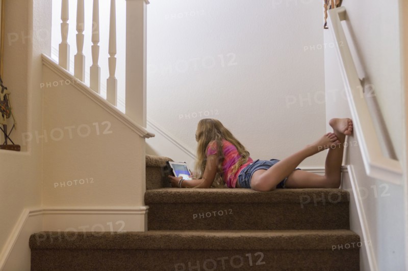 Caucasian girl using digital tablet on stairs
