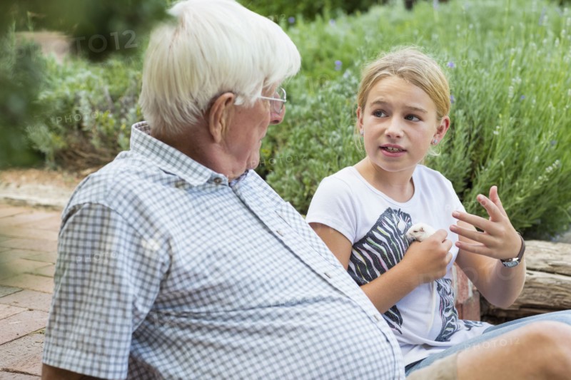 Caucasian grandfather and granddaughter talking in garden
