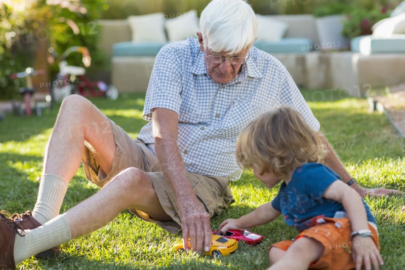 Caucasian grandfather and grandson playing on lawn