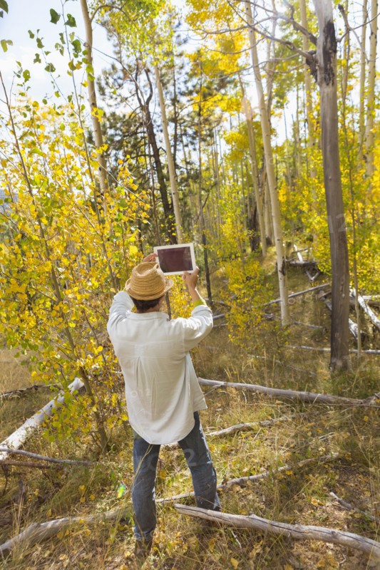 Man photographing with digital tablet in autumn forest