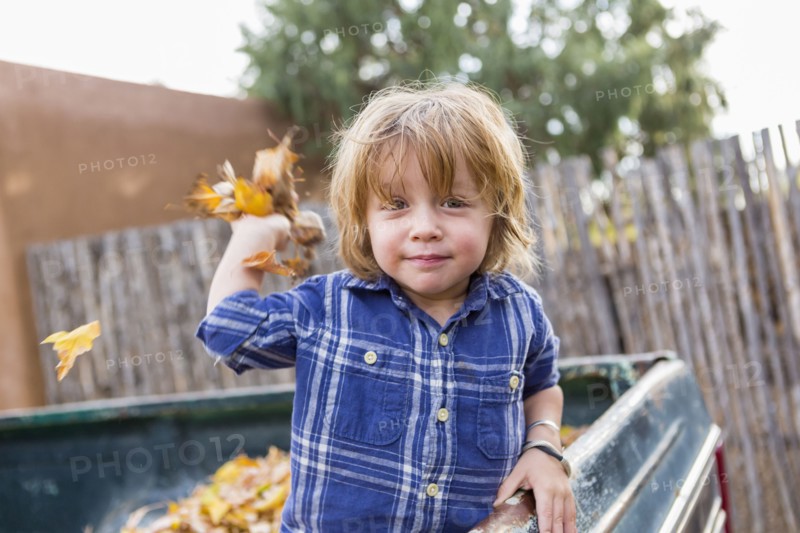 Caucasian boy playing in autumn leaves
