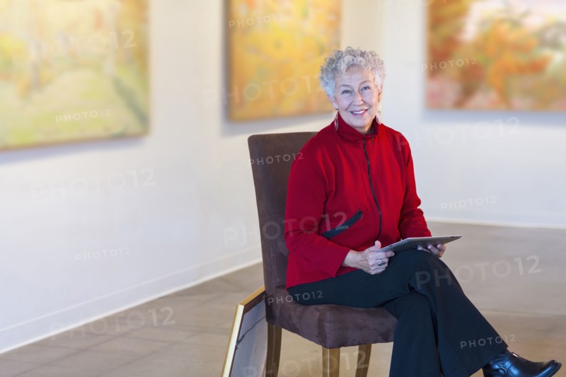 Older mixed race woman using digital tablet in art gallery