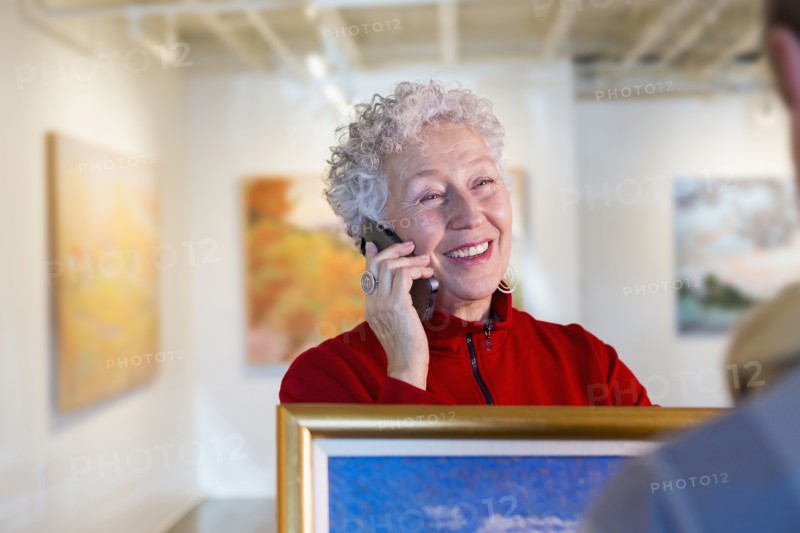 Older mixed race woman using cell phone in art gallery