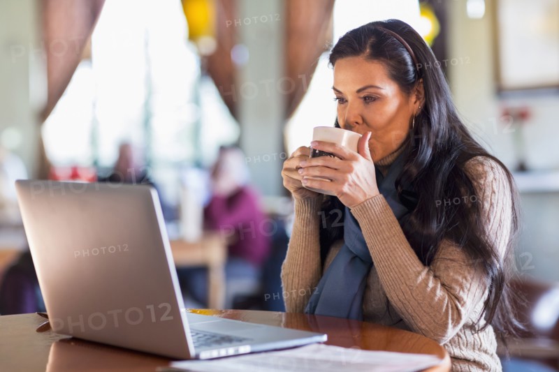 Hispanic woman using laptop in cafe