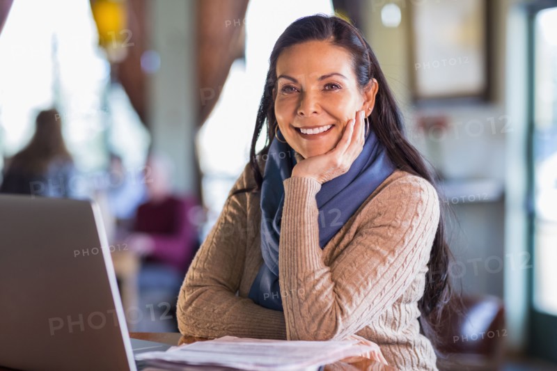Hispanic woman using laptop in cafe