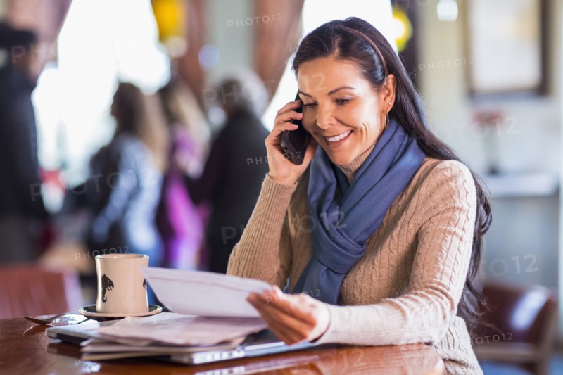 Hispanic woman talking on cell phone in cafe