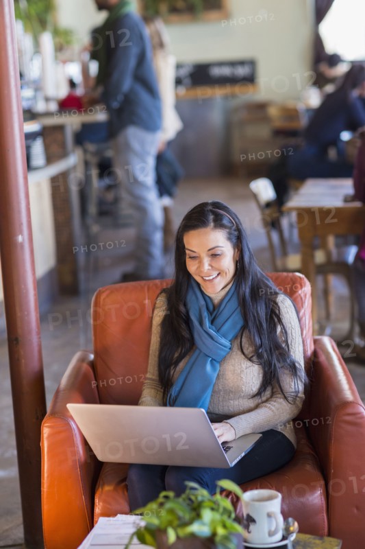 Hispanic woman using laptop in cafe
