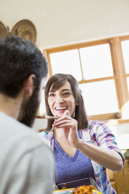 Hispanic woman serving boyfriend in kitchen
