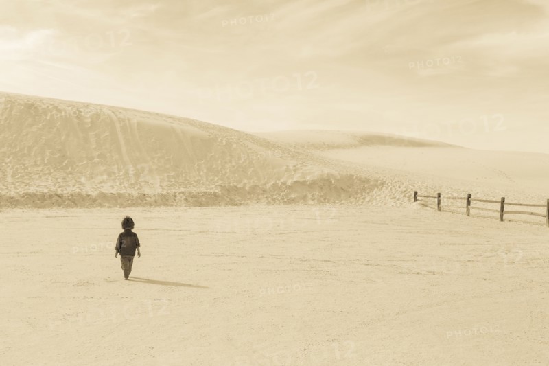 Caucasian preschooler boy walking in desert