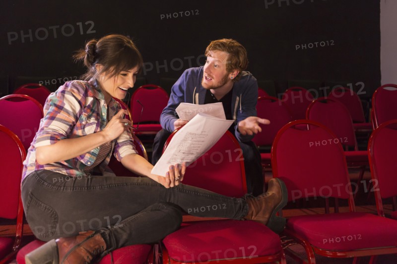 Actors rehearsing in red theater seats