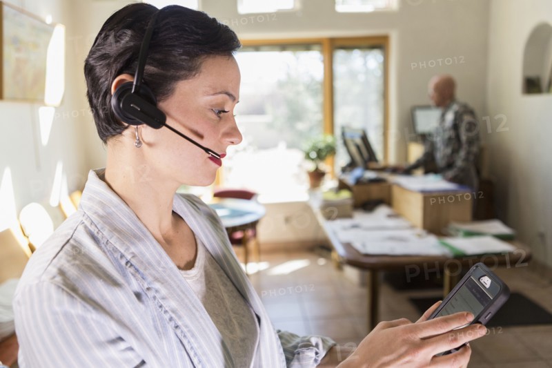 Businesswoman using digital tablet and headset in office