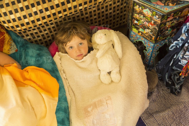Caucasian boy laying in blanket pile