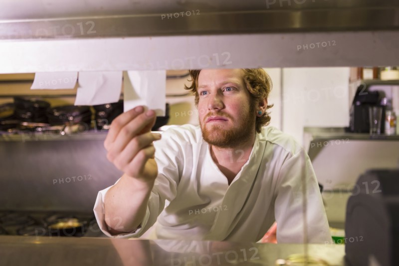 Caucasian chef reading orders in restaurant kitchen
